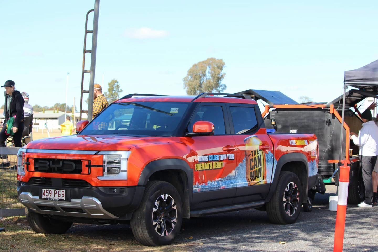 Red Can Man Coffee ute with its livery towing the matte-black coffee trailer at a daytime club event